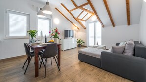 Una sala de estar moderna con comedor, vigas de madera en el techo y ventanas amplias.