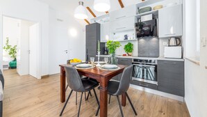 Una cocina moderna con armarios oscuros, horno empotrado y comedor con mesa y sillas de madera.
