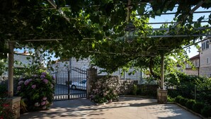 Un espace extérieur abrité, doté d’un mur en pierre, de plantes en pot et d’un portail en métal.