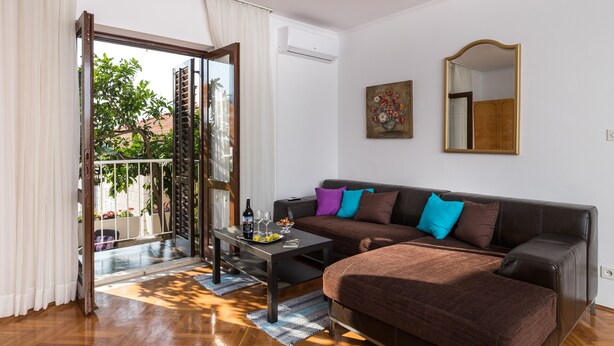 Un salon moderne comprenant un canapé, une table basse et une table à manger. Une porte-fenêtre coulissante donne accès à un espace extérieur.