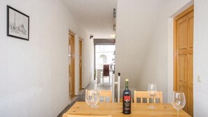 Een eetgedeelte met een houten tafel, twee wijnglazen en een fles wijn.