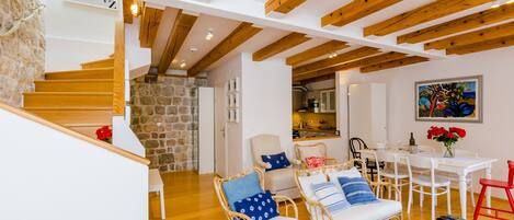 Uma sala de estar ampla com escada de madeira, móveis de vime e uma mesa de jantar.