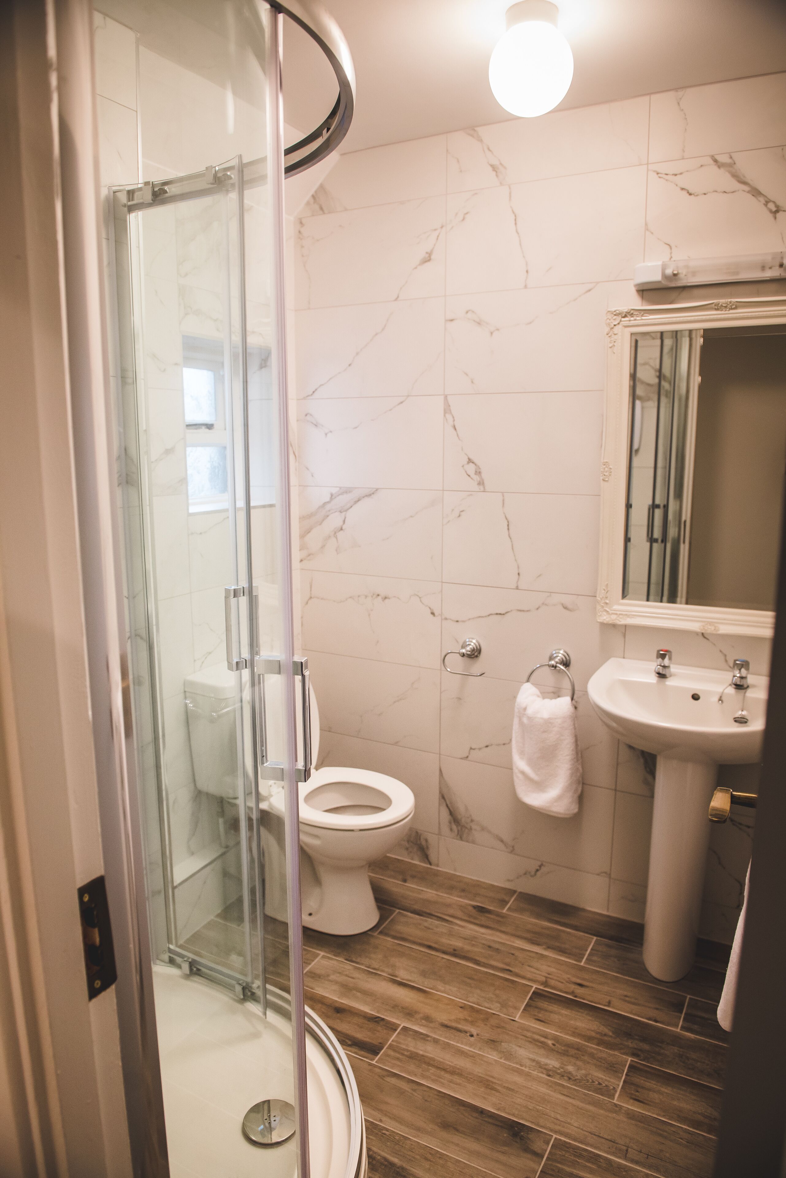 Een moderne badkamer met een douchecabine van glas, een toilet en een wastafel.