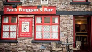 Un edificio de piedra con un marco rojo en la ventana y un cartel que dice "Jack Duggan's Bar".