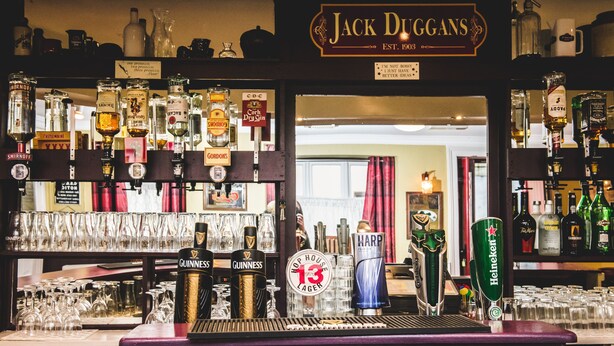 Un bar con múltiples grifos de cerveza, incluyendo Guinness y Heineken, y un letrero que dice "Jack Duggans".