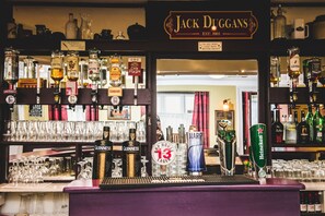 Un bar con múltiples grifos de cerveza, incluyendo Guinness y Heineken, y un letrero que dice "Jack Duggans".