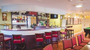 Zona de bar con mostrador, taburetes y mesa de billar.