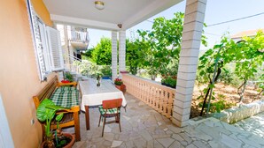 Un espacio de comedor al aire libre con techo, una mesa y sillas, plantas en macetas y vistas al entorno verde.