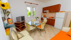 Una cocina compacta con comedor, televisor y refrigerador.