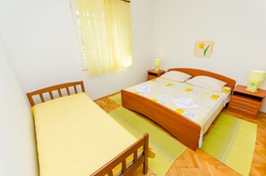Ein ordentlich eingerichtetes Schlafzimmer mit einem hölzernen Bett, einem Nachttisch mit Lampe und einem Fenster mit Vorhängen.