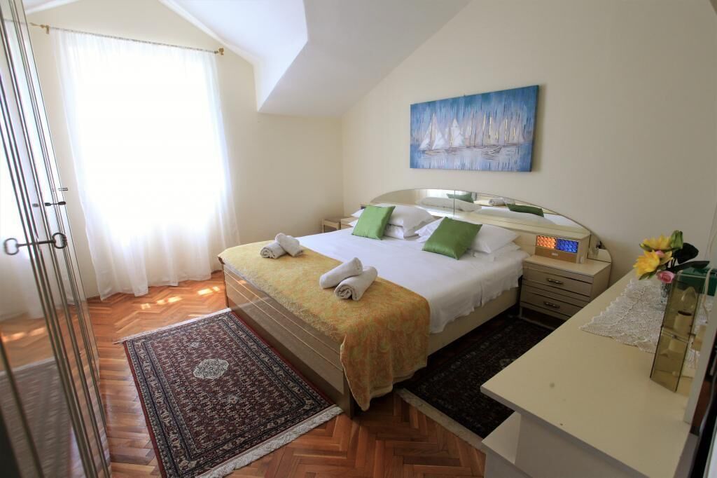A bedroom with a bed, bedside table, lamp, and a painting on the wall.