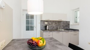 A modern kitchen with a grey countertop, a coffee maker, and a fruit bowl.