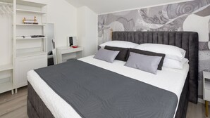 A neatly arranged bedroom with a bed, a desk, and a shelving unit.