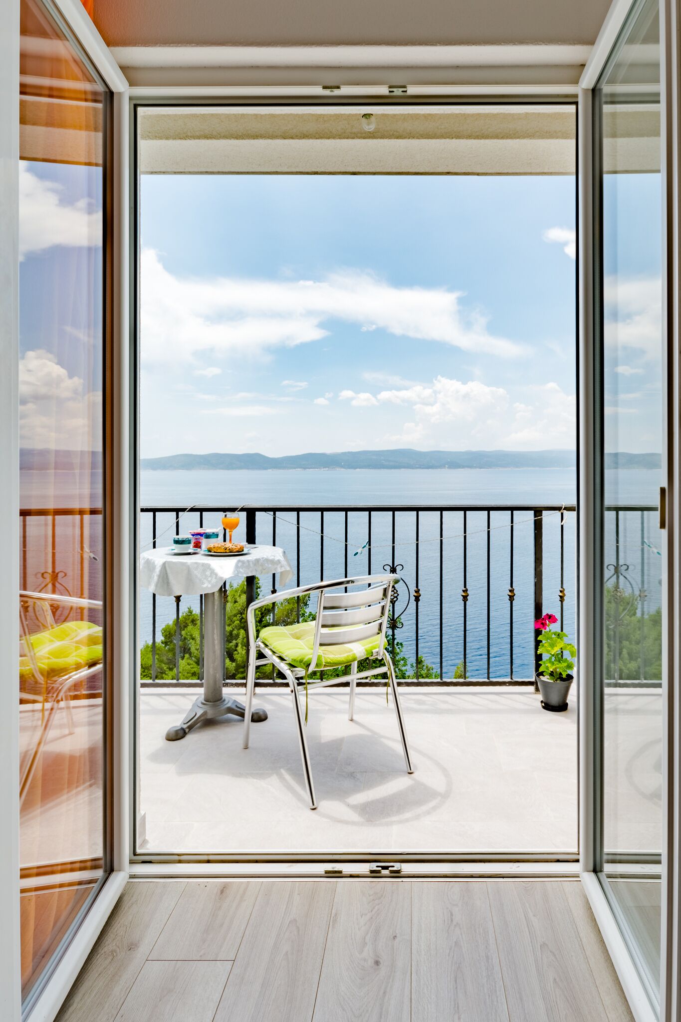 A balcony with a table and chairs, a view of the sea, and a railing.