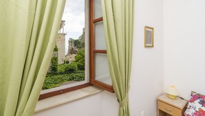 A room with a window, a nightstand with a lamp, and a framed picture on the wall. - Rooms Lovrijenac - Double Room with Sea View(1) (Dubrovnik)
