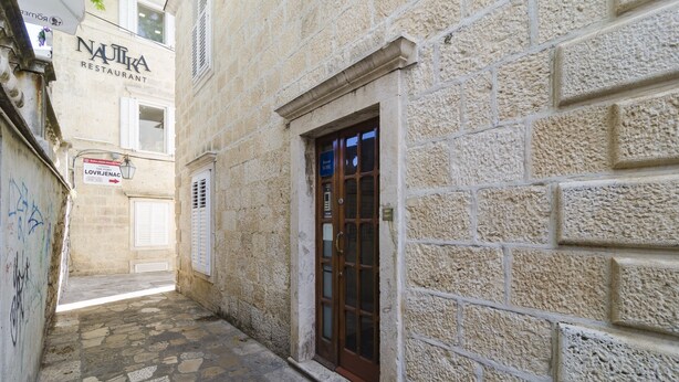 A narrow stone-paved alley with a building featuring a wooden door and a sign for 'NAUTIKA Restaurant'. - Rooms Lovrijenac - Double Room with Sea View(1) (Dubrovnik)