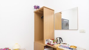 A small room with a wooden wardrobe, a desk with a chair, a lamp, and a small table with a plate of food and a kettle. - Rooms Lovrijenac - Double Room with Sea View(1) (Dubrovnik)
