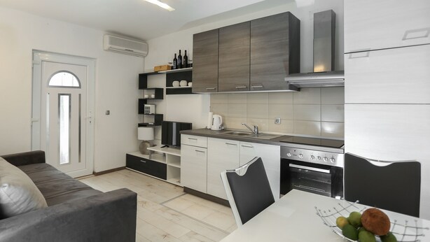 Una cocina moderna con armarios blancos, horno integrado y comedor con mesa y sillas.