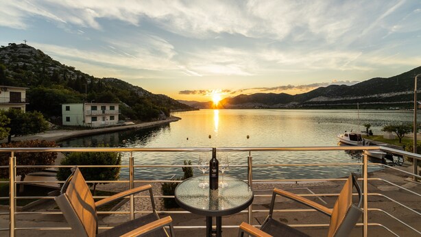 Una terraza con mesa y sillas que da a un lago al atardecer.