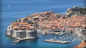 Un pueblo costero con arquitectura histórica, un puerto fortificado y un castillo destacado.