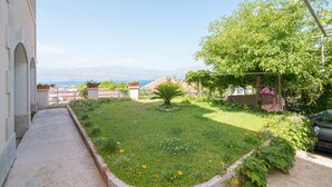 A garden with a pathway, a tree, and a view of the sea. - Apartments Ana & Bogdan (Postira)