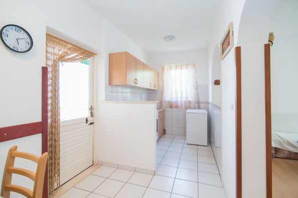 A kitchen with white cabinets, a refrigerator, and a clock on the wall. - Apartments Ana & Bogdan (Postira)