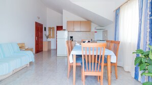 A compact living space with a dining area, kitchenette, and a sofa. - Apartments Ana & Bogdan (Postira)