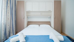 A hotel room with a bed, a wardrobe, a mirror, and a curtain. - Apartments Ana & Bogdan (Postira)