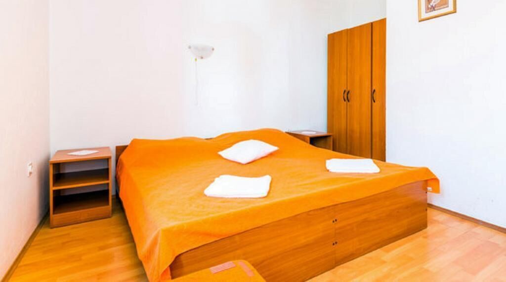 A bedroom with a wooden bed, a nightstand, a wardrobe, and a wall-mounted light.