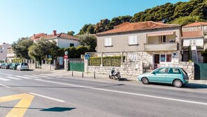 A street view with a two-story building, parked cars, and a clear sky.