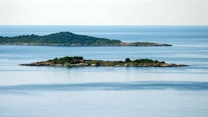 Une mer calme avec deux petites îles, l’une couverte d’arbres et l’autre d’un terrain rocheux.