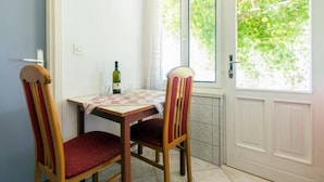Un coin repas avec une table et deux chaises, une bouteille de vin et une fenêtre donnant sur un paysage verdoyant.