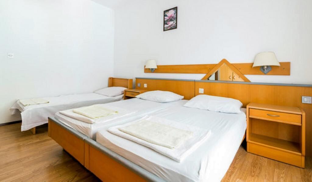 Hotellihuone, jossa on kaksi erillistä sänkyä, puinen pääty, yöpöytälamput ja pieni puinen yöpöytä.