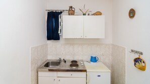 Een kleine keuken met een spoelbak, fornuis en keukenkastjes.