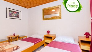 Habitació amb dos llits, ambira de fusta, un mirall, taules de nit i un quadre encimbellat a la paret.