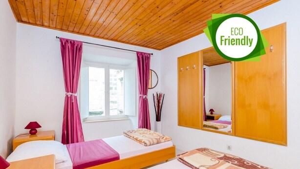 Habitació amb un llit, una taula petita, un mirall i una finestra amb cortines.