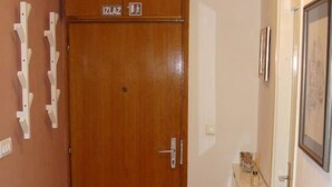 A wooden door with a sign above it, a small cabinet with a mirror, and a wall-mounted coat rack. - Apartment H&M (ST) - Two Bedroom Apartment with Balcony (Split)