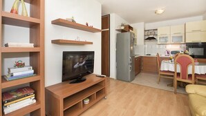 A compact living space with a TV on a wooden stand, a dining area with a table and chairs, and a kitchenette with a refrigerator and microwave. - Apartment H&M (ST) - Two Bedroom Apartment with Balcony (Split)
