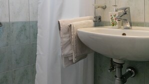 Un baño con un lavabo blanco, cabina de ducha de cristal y un espejo sobre el lavabo.
