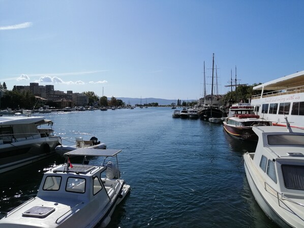 Un port de plaisance où sont amarrés différents types de bateaux, un pont en arrière-plan et des bâtiments le long de la rive.