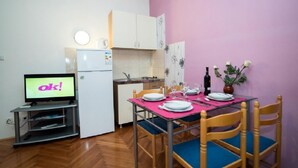 Una cucina compatta con frigorifero, forno a microonde e zona pranzo con tavolo apparecchiato per due.
