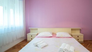 Una camera da letto con un letto, due comodini e una finestra con tende leggere.