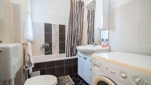 Un bagno completo di WC, lavandino, doccia e lavatrice.