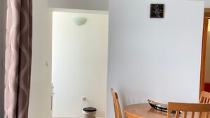 Comedor con mesa y sillas de madera, un cubo de basura y un aire acondicionado de pared.