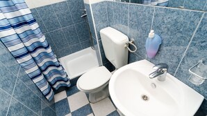 Un baño con inodoro y lavamanos blancos, y una ducha.