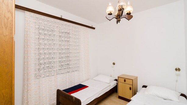 Un dormitorio con cama, mesita de noche, armario de madera y candelabro.