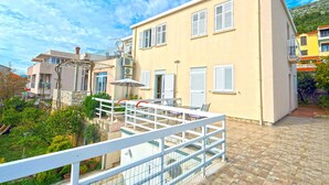A two-story building with a balcony, outdoor furniture, and a view of a hillside. - Villa Katarina - Double Room with Sea View (First Floor) (Dubrovnik)