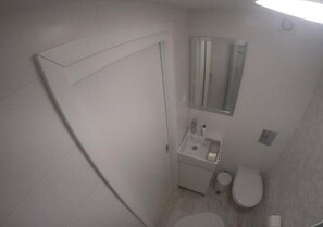 Een kleine, praktische badkamer met toilet, wastafel en spiegel.