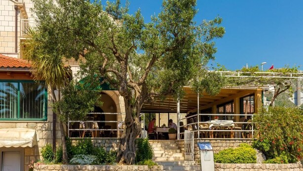 Ein Restaurant mit Außenbereich, Steinwänden und einem Baum im Vordergrund.