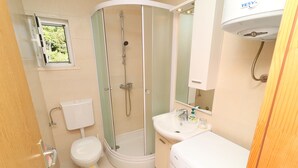 Une salle de bain avec une douche à parois de verre, des toilettes, un lavabo et un lave-linge.